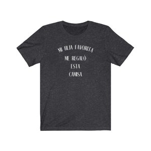 May include: Dark heather grey t-shirt with white text that reads "Mi hija favorita me regal&oacute; esta camisa".