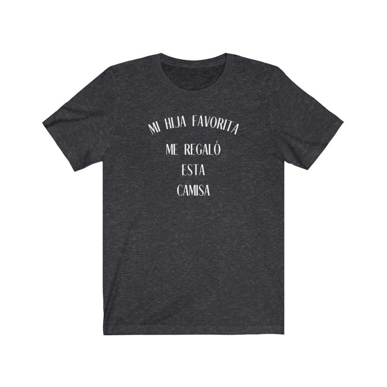 May include: Dark heather grey t-shirt with white text that reads "Mi hija favorita me regal&oacute; esta camisa".