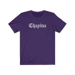 May include: A purple short-sleeved t-shirt with the word "Chapina" printed in white on the front.
