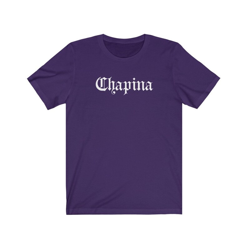 May include: A purple short-sleeved t-shirt with the word "Chapina" printed in white on the front.