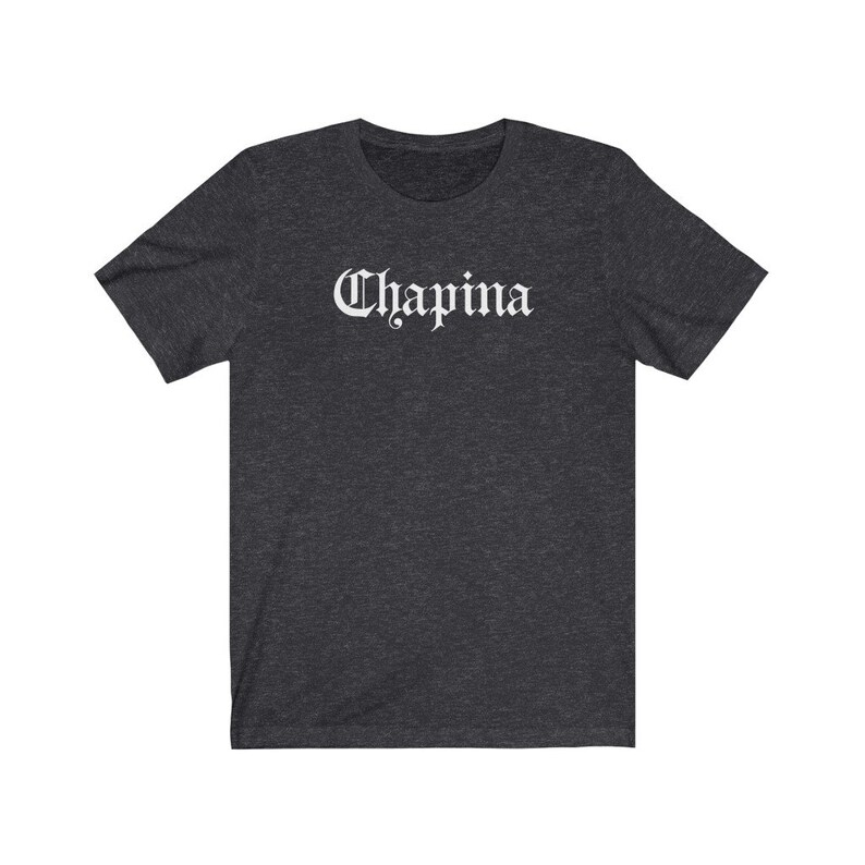 May include: A dark heather grey t-shirt with the word "Chapina" printed in white in a gothic font.