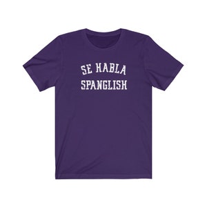 May include: Purple short-sleeved t-shirt with white text that reads "Se Habla Spanglish".