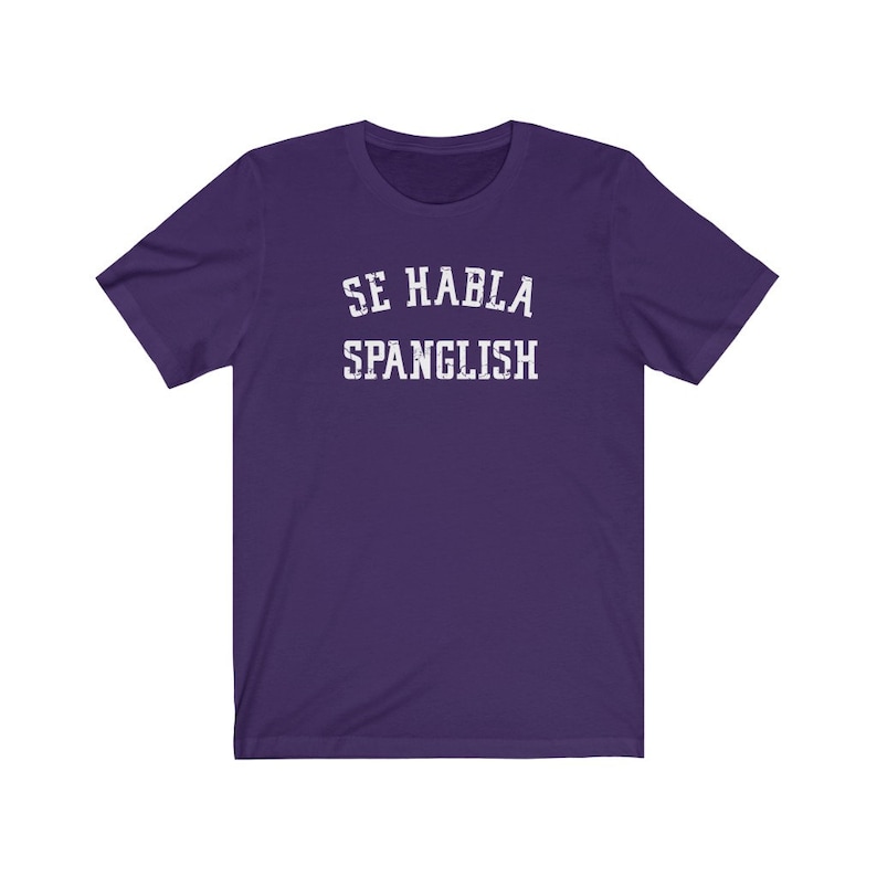 May include: Purple short-sleeved t-shirt with white text that reads "Se Habla Spanglish".