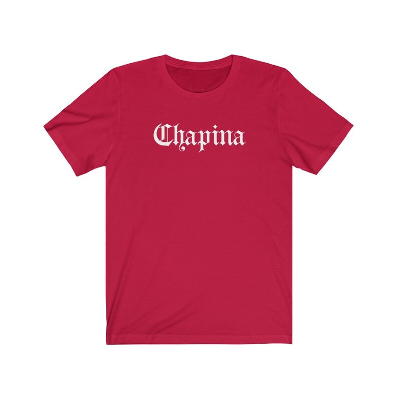 May include: Red short-sleeved t-shirt with the word "Chapina" printed in white in a gothic font.