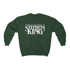 May include: A dark green sweatshirt with white text that reads "Based on the novel by Stephen King".