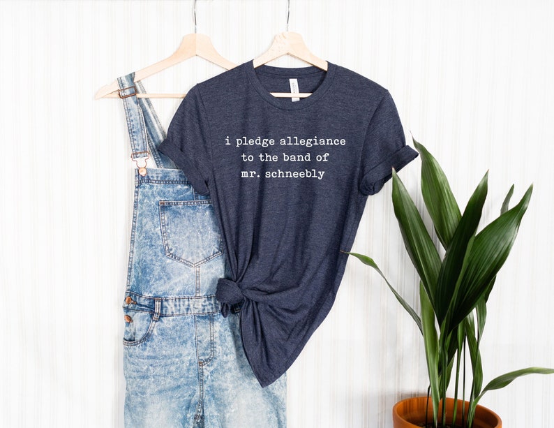 Puede incluir: Una camiseta azul oscuro con el texto "i pledge allegiance to the band of mr. schneebly" impreso en blanco.