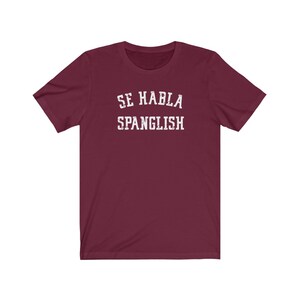 May include: Burgundy short-sleeved t-shirt with white text that reads "Se Habla Spanglish".