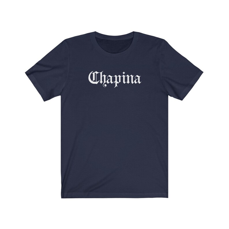 May include: A navy blue t-shirt with the word "Chapina" printed in white in a gothic font.