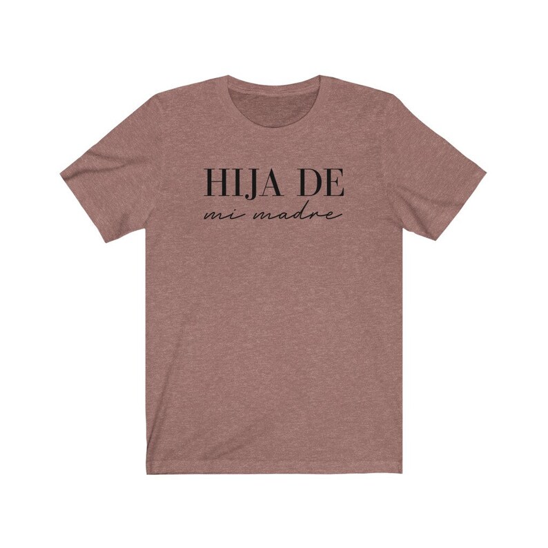 May include: A heather brown t-shirt with the text "HIJA DE mi madre" in black.