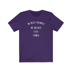 May include: Purple t-shirt with white text that reads "Mi hija favorita me regal&oacute; esta camisa".