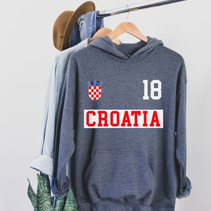 May include: A dark gray hooded sweatshirt with a red and white Croatian flag patch, the number 18, and the word "CROATIA" in red letters.