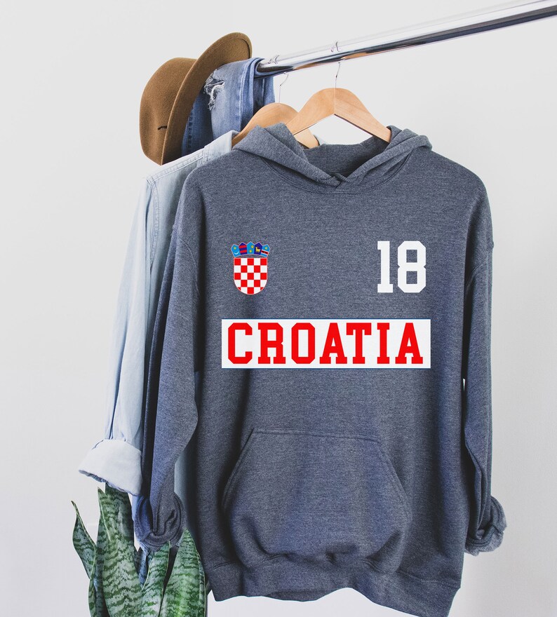 May include: A dark gray hooded sweatshirt with a red and white Croatian flag patch, the number 18, and the word "CROATIA" in red letters.