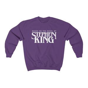 May include: Purple sweatshirt with white text that reads "Based on the novel by Stephen King"