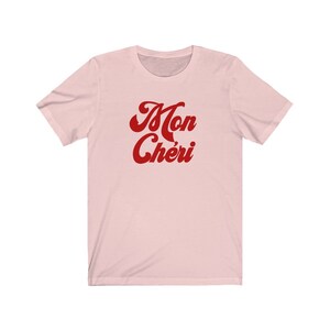 May include: A pink t-shirt with the text "Mon Ch&eacute;ri" in red cursive lettering.