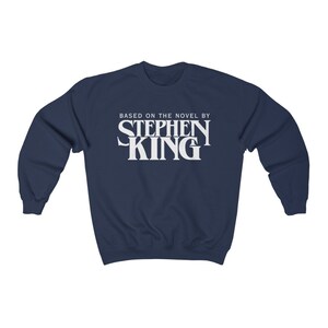 May include: A navy blue sweatshirt with white text that reads "Based on the novel by Stephen King".