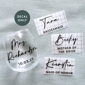 May include: Four clear vinyl stickers with black script text. The stickers read "Tara Bridesmaid", "Becky Mother of the Bride", "Kiersten Maid of Honor", and "Mrs. Richardson 10.03.25".