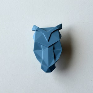 Pode incluir: Uma escultura de coruja geométrica azul feita de material impresso em 3D.