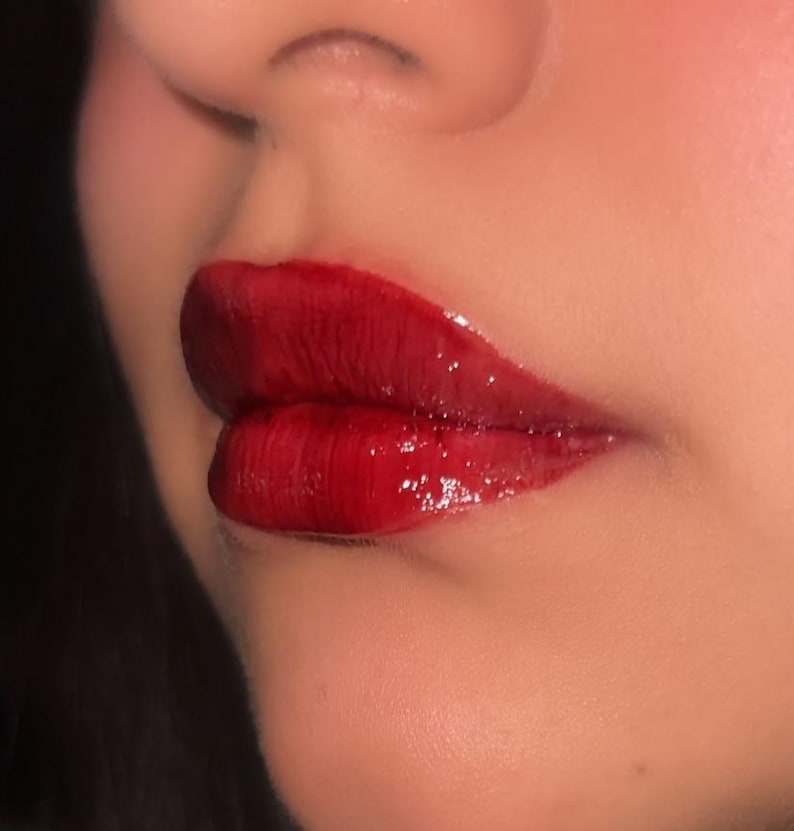 Pode incluir: Close-up dos l&aacute;bios de uma pessoa usando um batom vermelho escuro brilhante.
