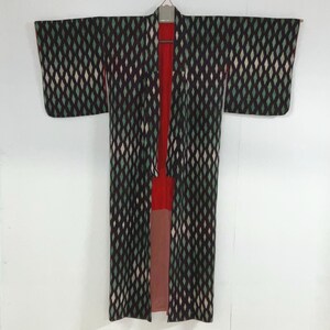 May include: A vintage kimono with a diamond pattern in black, green, and white. The interior lining is red and pink. The kimono is hanging on a hanger against a white background.
