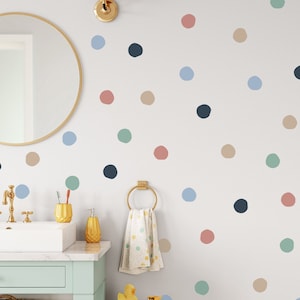 May include: A white wall with a polka dot pattern in various colors, including blue, green, pink, and brown. The dots are different sizes and are randomly placed on the wall.
