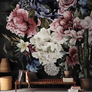 May include: A dark floral wallpaper mural with a large bouquet of pink, white, and blue flowers. The wallpaper is displayed in a living room setting with a wooden bench, a rug, and a lamp.
