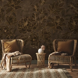 May include: Two wicker chairs with brown cushions sit in front of a wall with a brown floral wallpaper pattern. A small table with a vase of pink flowers sits between the chairs.