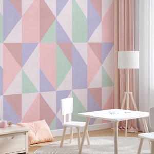 Puede incluir: Una mesa blanca y dos sillas blancas con patas de madera en una habitación con un papel tapiz de patrón geométrico rosa, verde y morado.