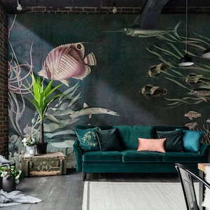 Puede incluir: Un sof&aacute; de terciopelo verde azulado con un coj&iacute;n rosa se encuentra frente a un mural de pared que representa una variedad de peces y algas marinas. El mural est&aacute; pintado en tonos de verde, azul y marr&oacute;n.