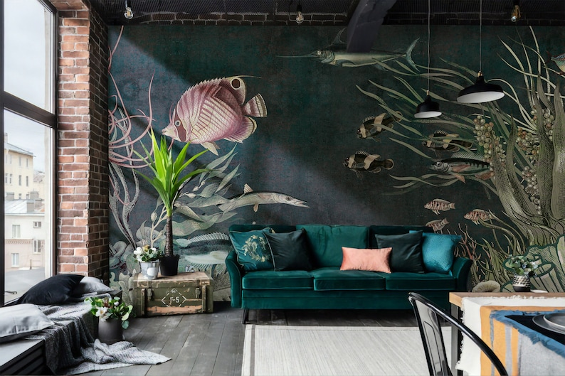 Puede incluir: Un sof&aacute; de terciopelo verde azulado con un coj&iacute;n rosa se encuentra frente a un mural de pared que representa una variedad de peces y algas marinas. El mural est&aacute; pintado en tonos de verde, azul y marr&oacute;n.