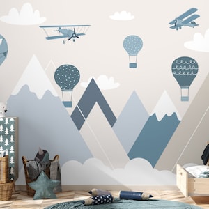 May include: A blue and white nursery wall mural with a mountain range, clouds, hot air balloons, and airplanes. The mural is perfect for a child's room.