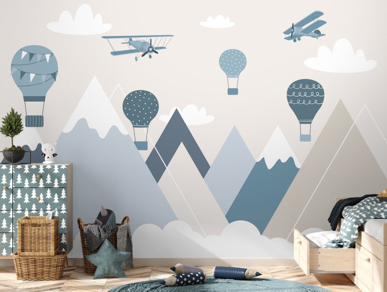 May include: A blue and white nursery wall mural with a mountain range, clouds, hot air balloons, and airplanes. The mural is perfect for a child's room.