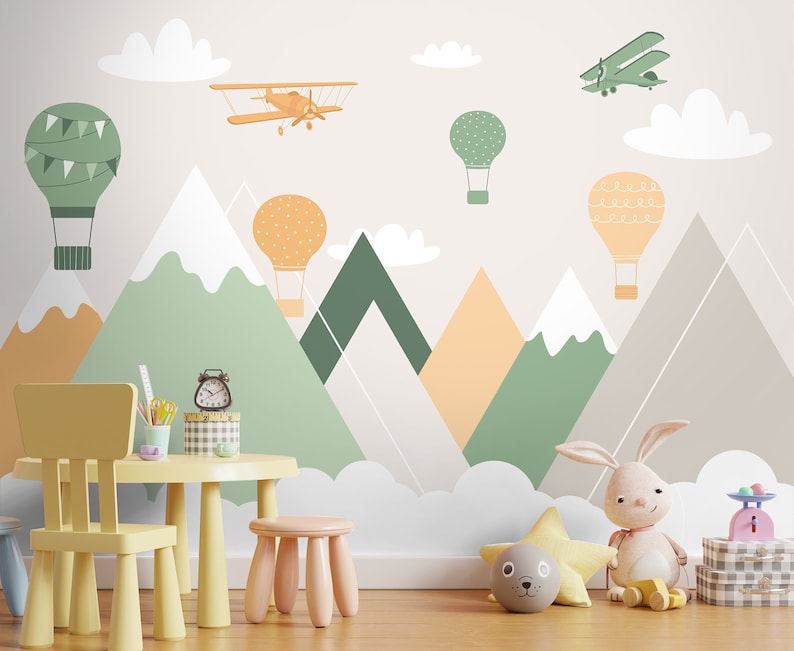 May include: A children's playroom with a light gray wall featuring a whimsical mural of mountains, clouds, hot air balloons, and airplanes. A yellow child's chair and table are in the foreground, along with a stuffed bunny and other toys.