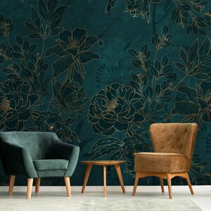 May include: Two armchairs, one green velvet and one brown velvet, are placed in front of a teal wall with a gold floral pattern. A small wooden table sits between the chairs.