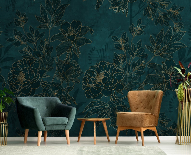 May include: Two armchairs, one green velvet and one brown velvet, are placed in front of a teal wall with a gold floral pattern. A small wooden table sits between the chairs.