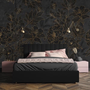 May include: A black upholstered bed with a headboard featuring a tufted design. The bed is positioned in front of a wall with a black and gold floral wallpaper. The wallpaper features a large-scale floral pattern with delicate gold outlines.