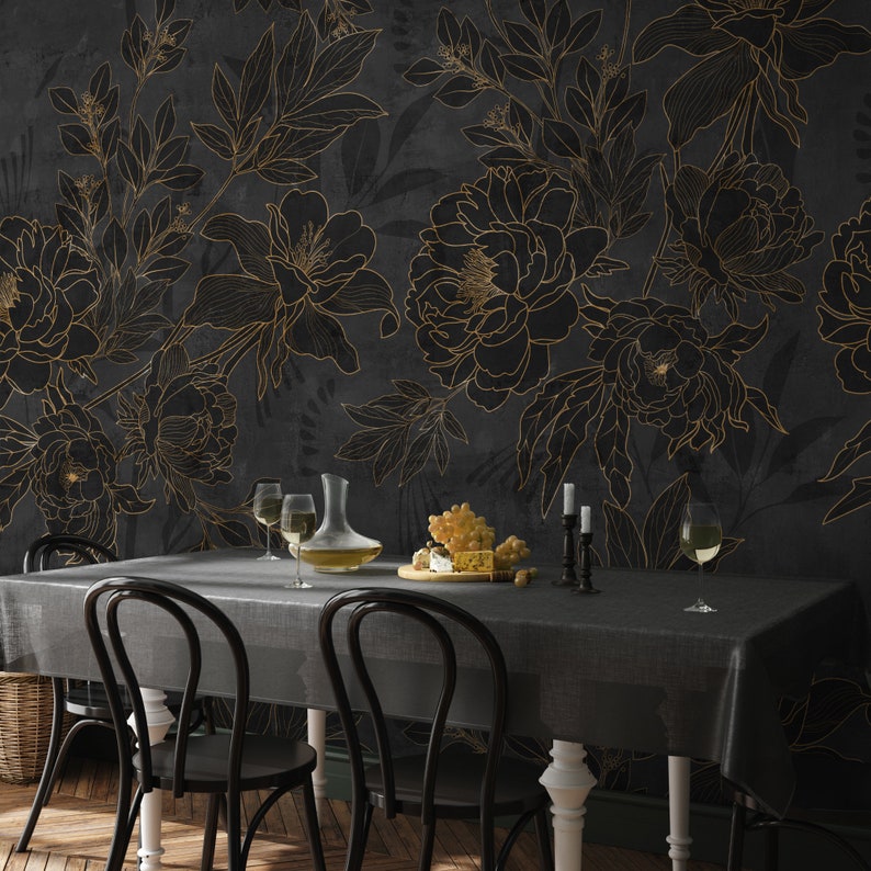 May include: A black dining table with six chairs set against a dark gray wall with a gold floral pattern. The table is set with glasses, a decanter, and a bowl of fruit.