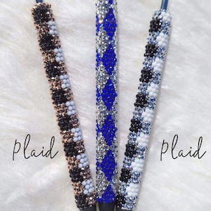May include: Three pens with different rhinestone designs. The pen on the left has a black and white plaid design with rose gold accents. The middle pen has a blue and silver diamond design. The pen on the right has a black and white plaid design. The text "Diamond" is above the pens and the text "Plaid" is below the pens.