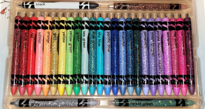 May include: A set of 28 glitter gel pens in a variety of colors, including black, red, orange, yellow, green, blue, purple, pink, and gray. The pens are arranged in a clear plastic case.
