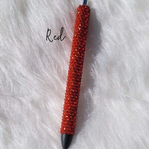 May include: Red rhinestone pen with a black tip. The pen is covered in red rhinestones.
