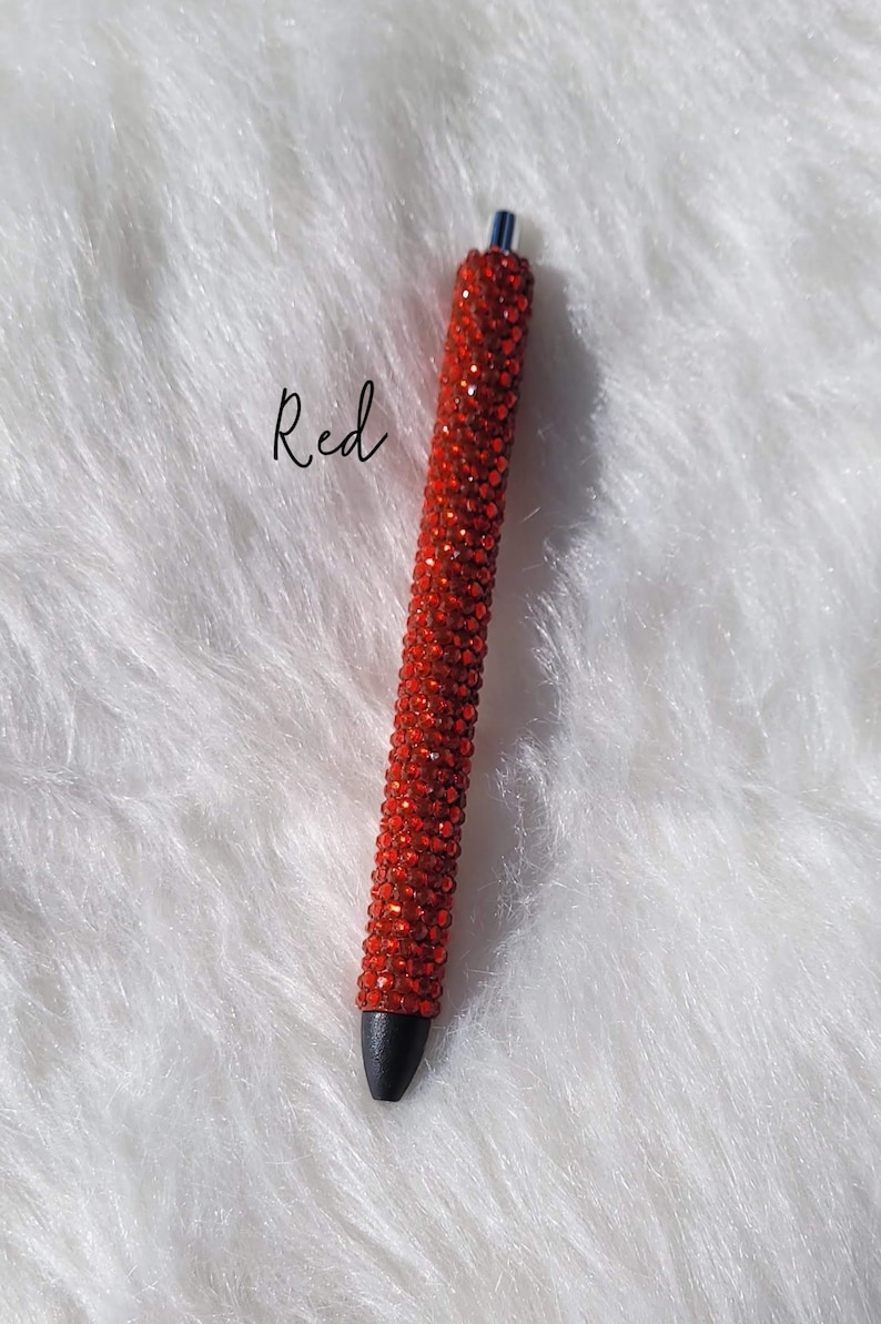 May include: Red rhinestone pen with a black tip. The pen is covered in red rhinestones.