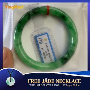 May include: A vibrant green jadeite bangle bracelet with dark green inclusions. The bracelet is accompanied by a tag from PNJ Laboratory, indicating it is natural jade. A free jade necklace is offered with orders over $200.