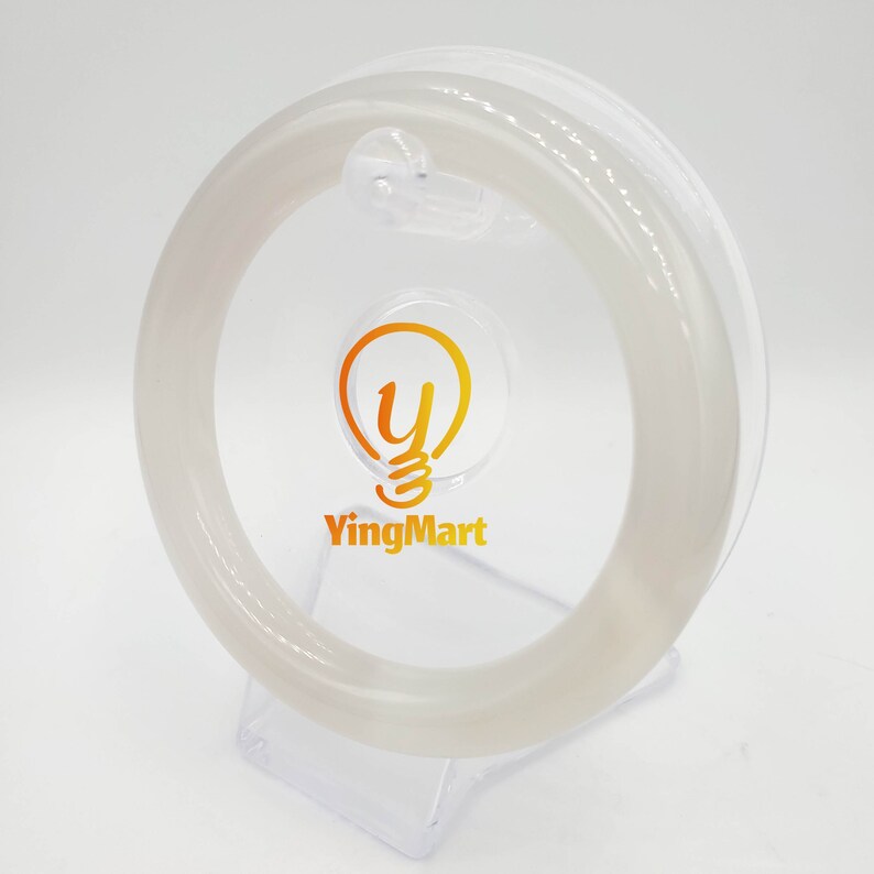 May include: A white jade bangle bracelet on a clear plastic stand. The bangle is smooth and polished. The stand has a light bulb logo with the text "YingMart".