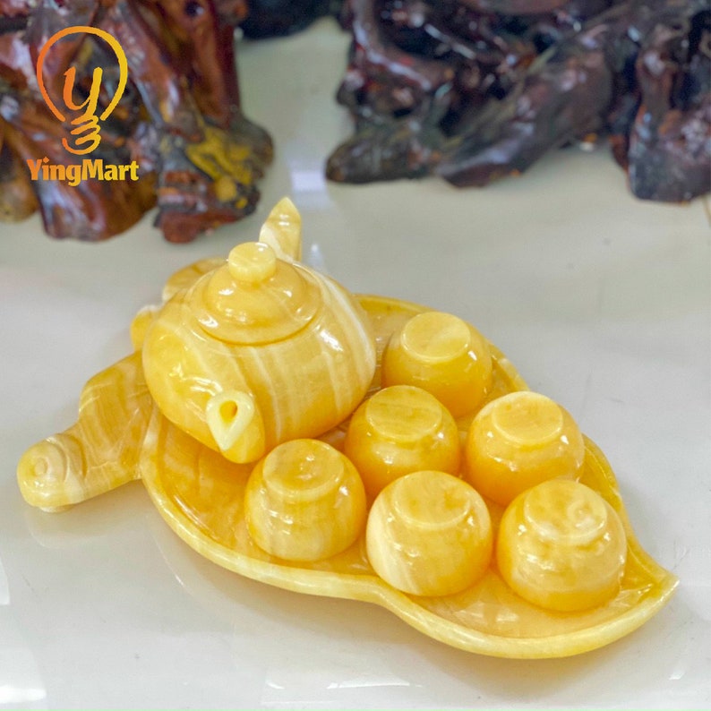 May include: A yellow marble tea set with a teapot and six cups, all sitting on a leaf-shaped tray.