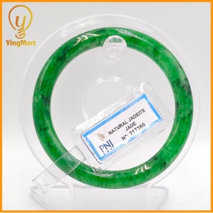 May include: A green jadeite bangle bracelet with a white tag that reads "NATURAL JADEITE JADE N°: 217380 PNJ AMO MONET ONE D"