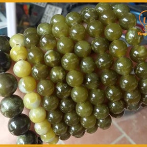 May include: A close-up of a green and yellow beaded bracelet. The beads are round and have a smooth, polished finish. The bracelet is made of natural stone.