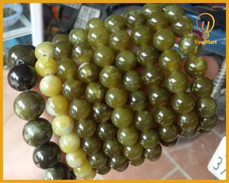May include: A close-up of a green and yellow beaded bracelet. The beads are round and have a smooth, polished finish. The bracelet is made of natural stone.