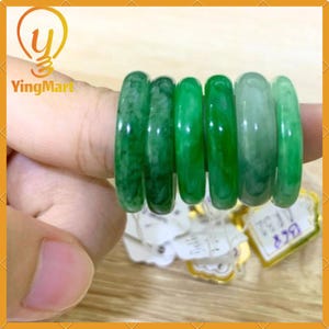 May include: Five jade green rings stacked on top of each other. The rings are smooth and polished.