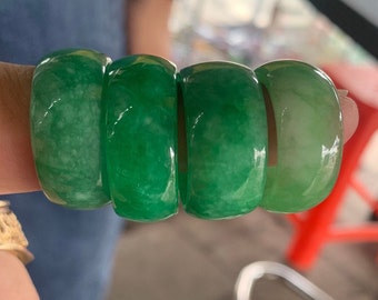 Pode incluir: Quatro anéis de jade empilhados uns sobre os outros. Os anéis são de cor verde claro e têm um acabamento liso e polido.