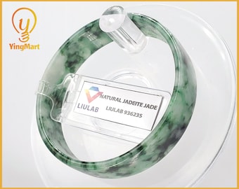 May include: A green jadeite jade bangle bracelet with black and white markings. The bracelet is displayed on a clear stand with a label that reads "NATURAL JADEITE JADE LIULAB 936235".