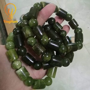 May include: A close-up of a green jade bracelet with round and cylindrical beads. The bracelet is made of natural stone and has a polished finish.